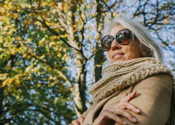 Portrait of smiling woman wearing scarf and sunglasses in a park